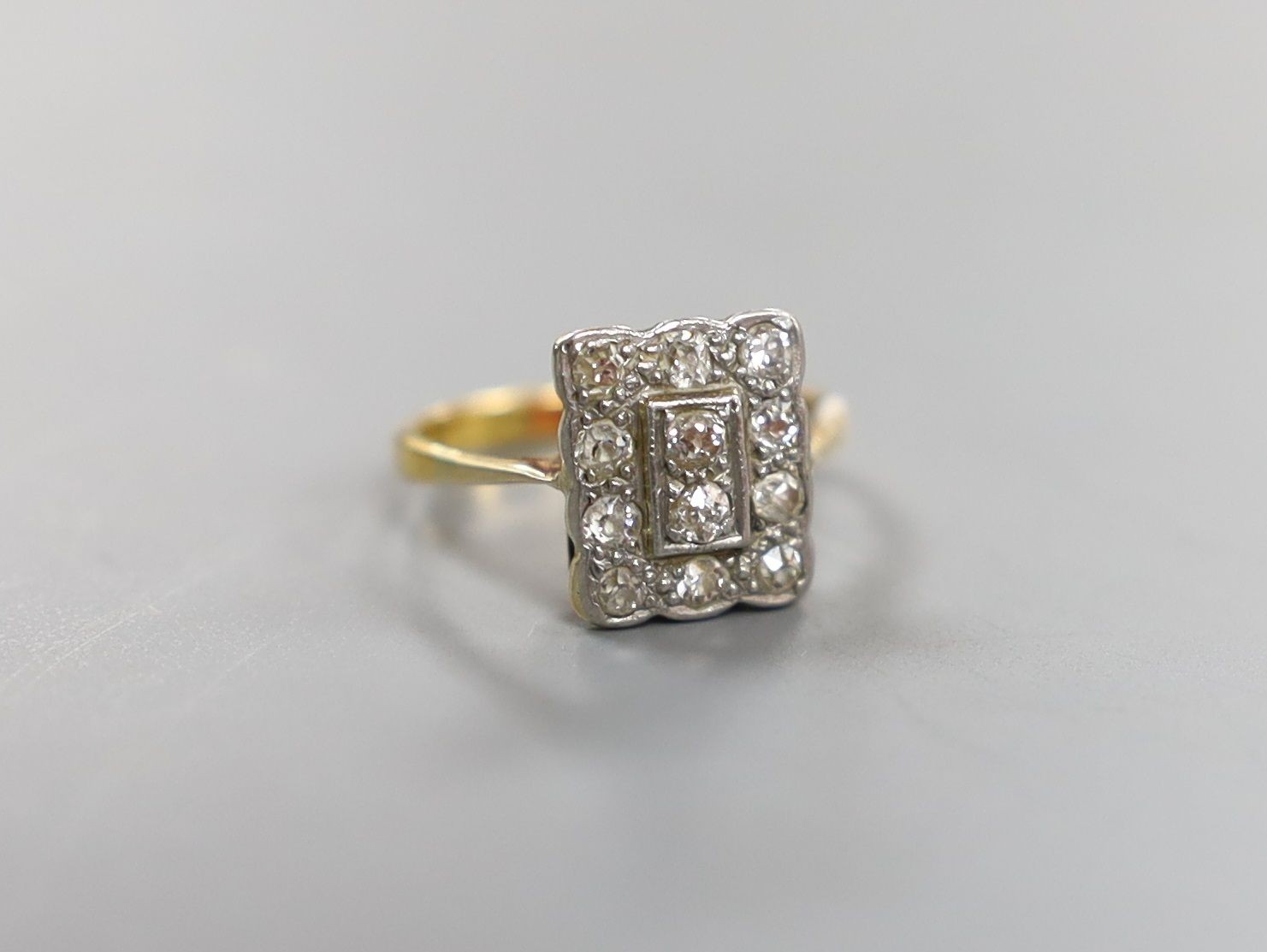 A 1920's yellow metal and diamond cluster set tablet ring, size F, gross weight 2.3 grams.